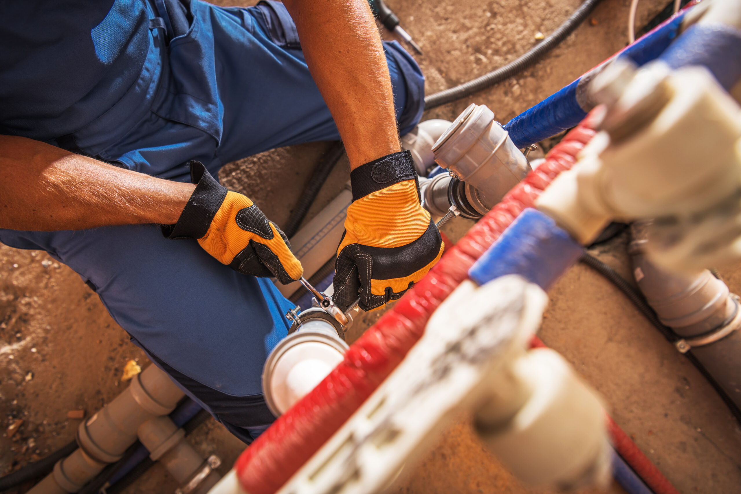 professional plumber repairing pipes with tools in a construction area